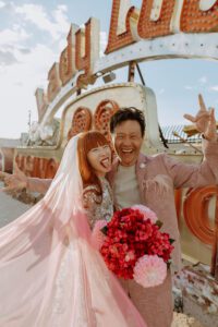 A fun and colorful 10-year vow renewal at the Little White Chapel and Neon Museum in Las Vegas! This Berlin-based couple brought their dog Goji all the way from Germany to celebrate in true retro Vegas style—pink Cadillac, feathers, sparkles, and all. The perfect inspo for modern couples who want playful, stylish, and unforgettable elopement vibes.